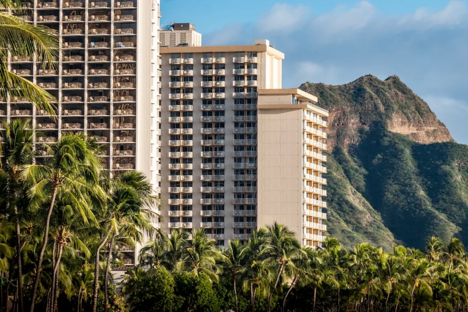High-rise apartment buildings in Waikiki, Hawaii with steep green mountains in background.